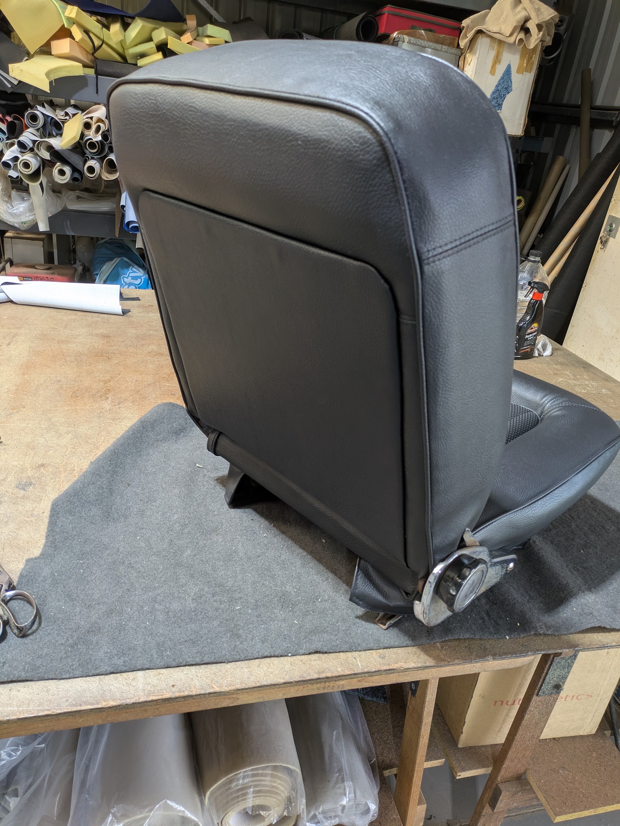 A black vinyl seat back finished and standing on the workbench at Brewster's Motor Trimming