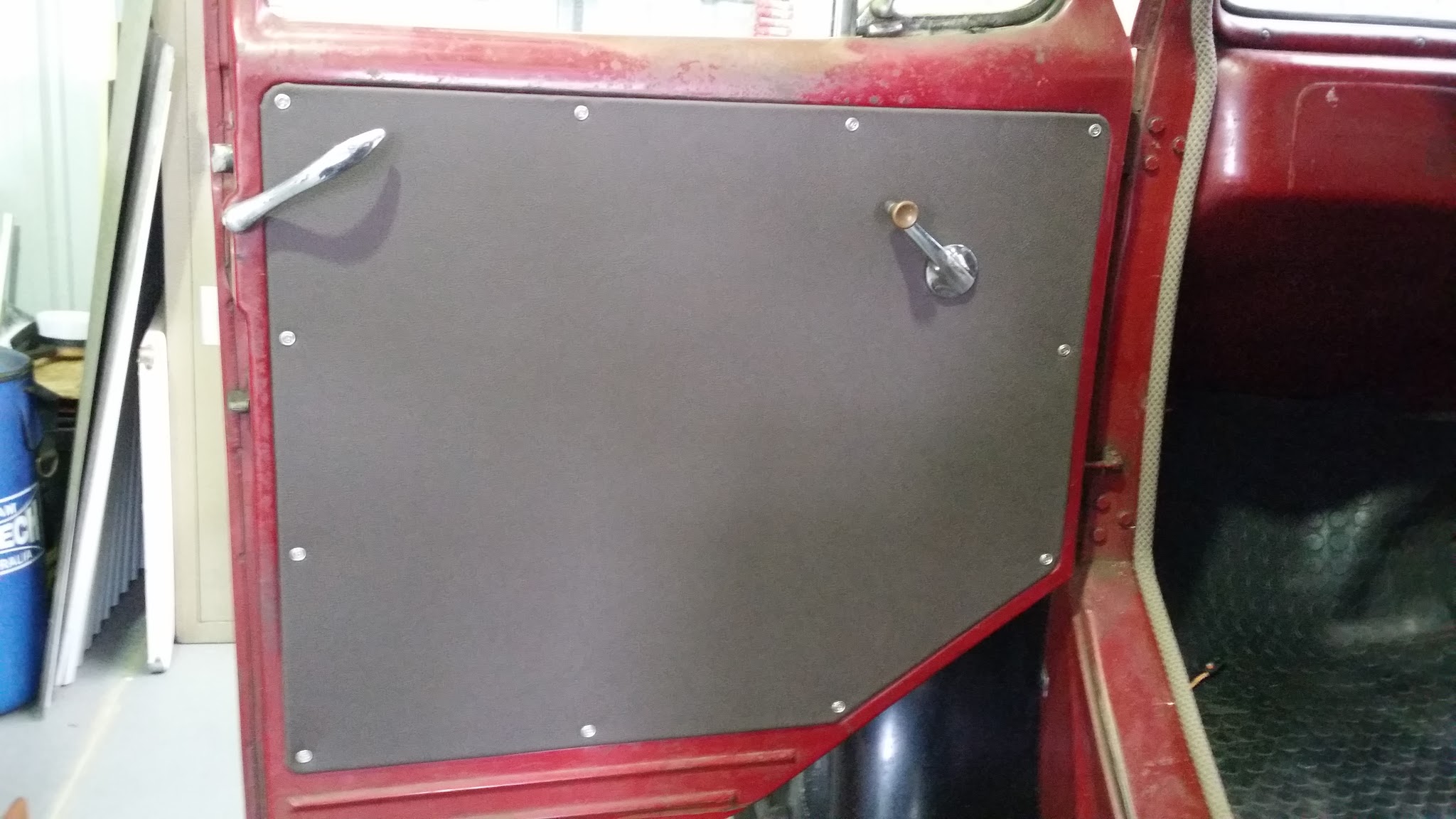 A new black door trim panel fitted to the door of a vintage red truck