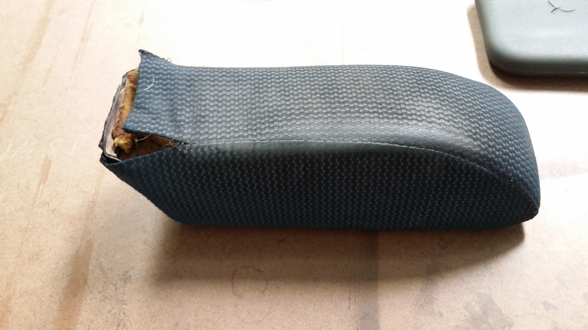 A small armrest part recovered in black vinyl on the workbench